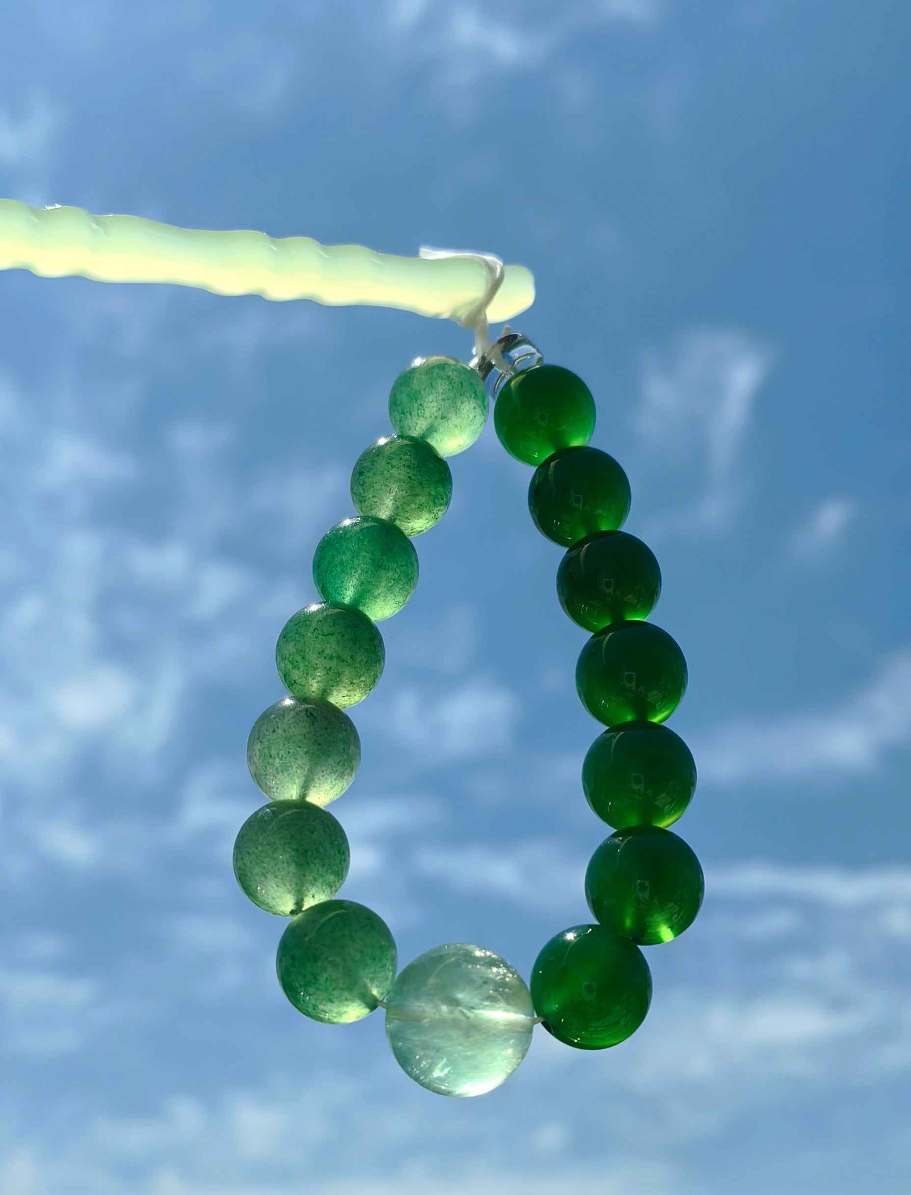 Great Forest Wood — 大林木 bracelet held against blue sky